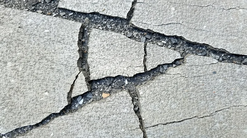 Cracked concrete surface showing a network of structural cracks on aged infrastructure